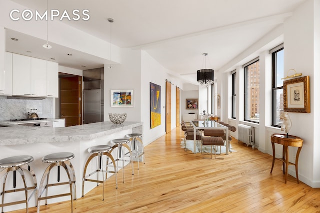 1 Hudson St Unit 9, New York City, NY 10013 - kitchen with radiator, stainless steel built in refrigerator, light wood-style flooring, tasteful backsplash, and a breakfast bar