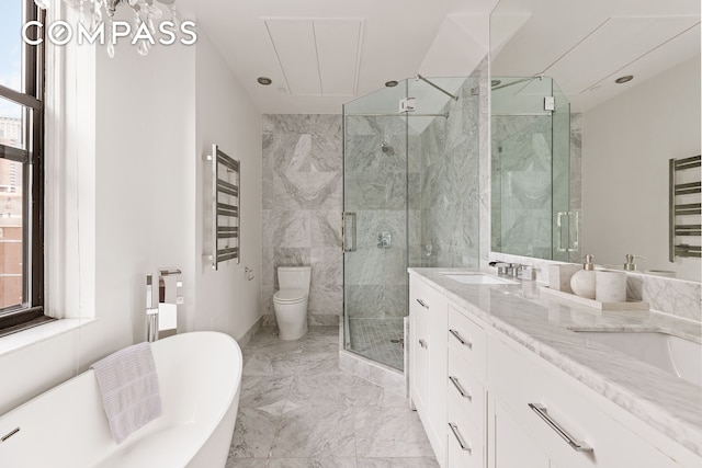 full bathroom with marble tiled floors, a marble finish shower, a freestanding tub, double vanity, and toilet