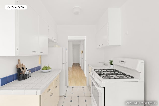 100 La Salle St Unit 10C, New York City, NY 10027 - kitchen featuring white appliances, white cabinetry, tile counters, and light tile patterned floors