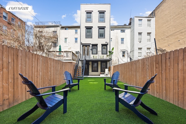 view of property's community featuring stairs, a fenced backyard, a wooden deck, and a lawn
