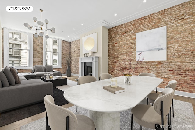 dining space featuring wood finished floors, visible vents, a fireplace, brick wall, and a notable chandelier