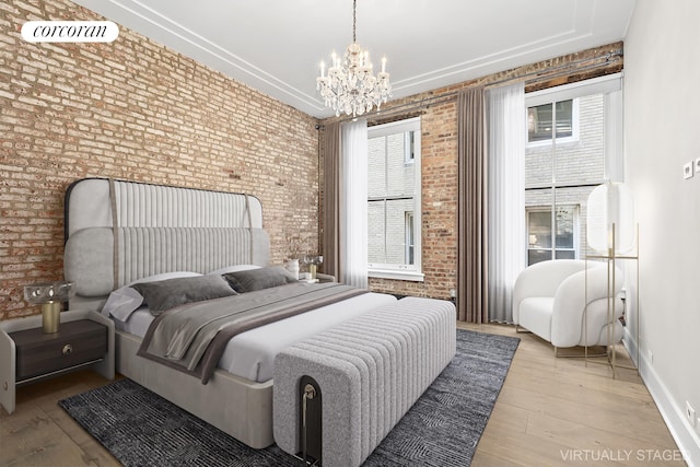 bedroom featuring wood-type flooring, brick wall, and an inviting chandelier
