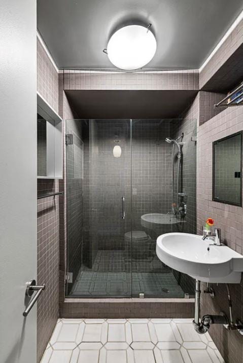 full bath with a sink, a stall shower, tile walls, toilet, and a bidet