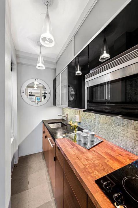 kitchen featuring butcher block countertops, a sink, black stovetop, stainless steel microwave, and backsplash