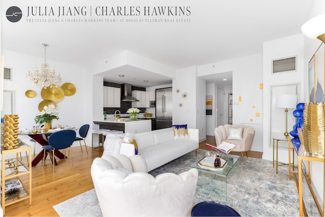 living area featuring a chandelier, visible vents, light wood finished floors, and baseboards