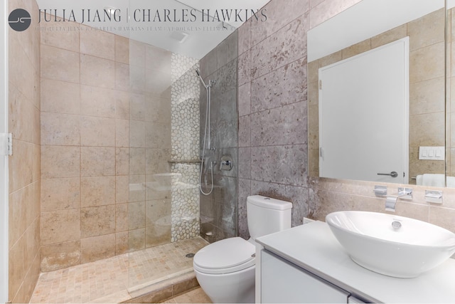 full bathroom featuring toilet, a walk in shower, vanity, and tile walls