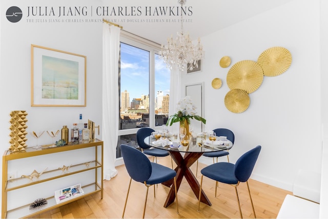 dining area featuring a chandelier, baseboards, wood finished floors, and a view of city