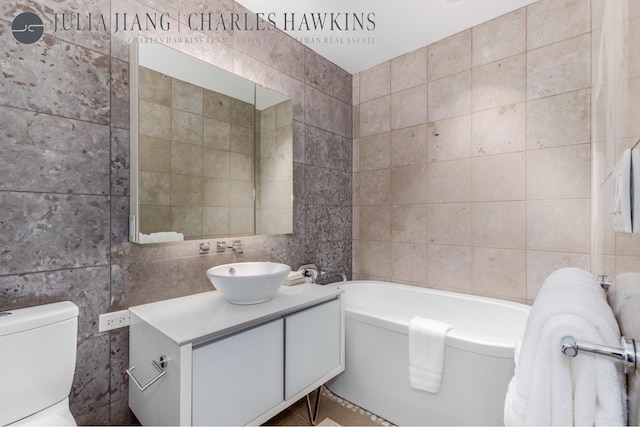 bathroom with tile walls, toilet, a garden tub, and vanity