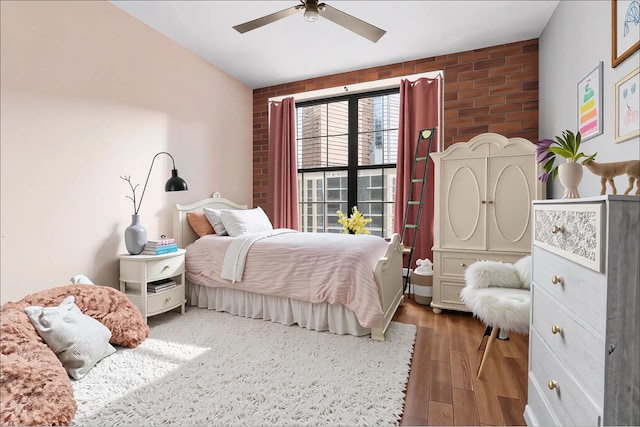 42-60 Crescent St Unit 7D, New York City, NY 11101 - bedroom with brick wall, ceiling fan, and wood finished floors