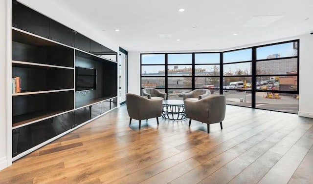 living area with a wall of windows, light wood finished floors, and a wealth of natural light