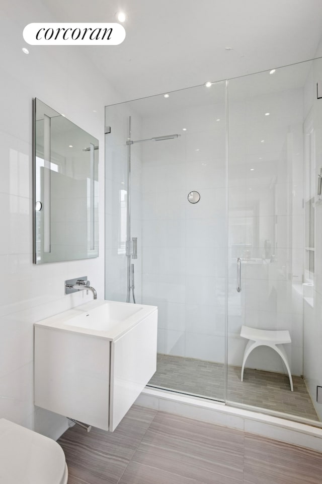 bathroom featuring toilet, a stall shower, and vanity