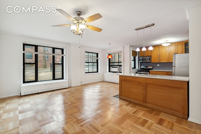 355 Clinton Ave Unit 1F, New York City, NY 11238 - kitchen with appliances with stainless steel finishes, brown cabinets, light countertops, a peninsula, and hanging light fixtures