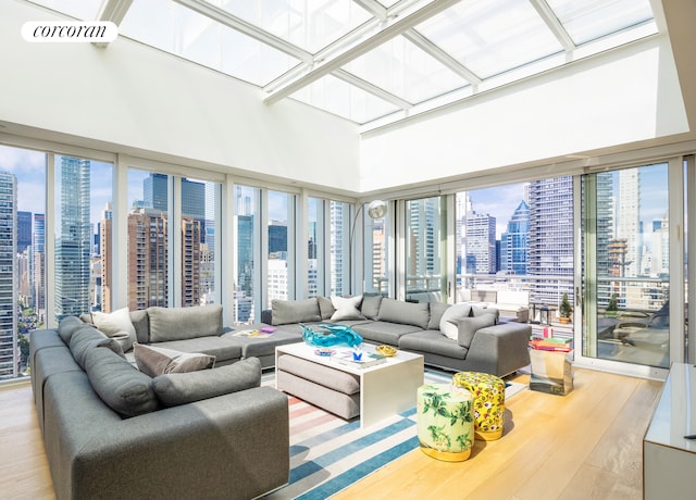 301 E 61st Street Penthouse, New York City, NY 10065 - living area featuring a view of skyline, wood finished floors, a skylight, and a towering ceiling