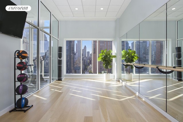 301 E 61st Street Penthouse, New York City, NY 10065 - workout area with wood finished floors, a skyline view, a drop ceiling, and recessed lighting