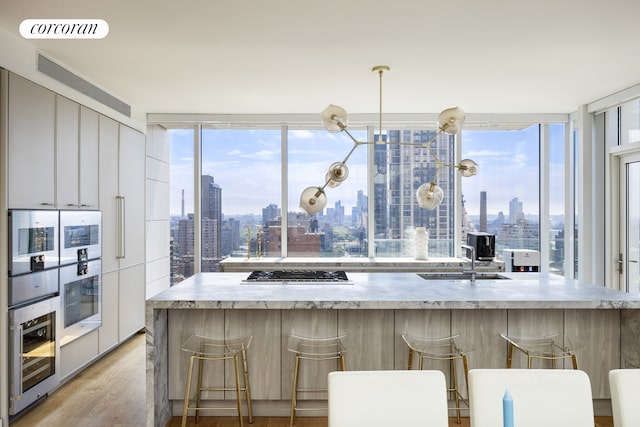 301 E 61st Street Penthouse, New York City, NY 10065 - kitchen featuring a view of skyline, beverage cooler, stainless steel gas cooktop, and modern cabinets