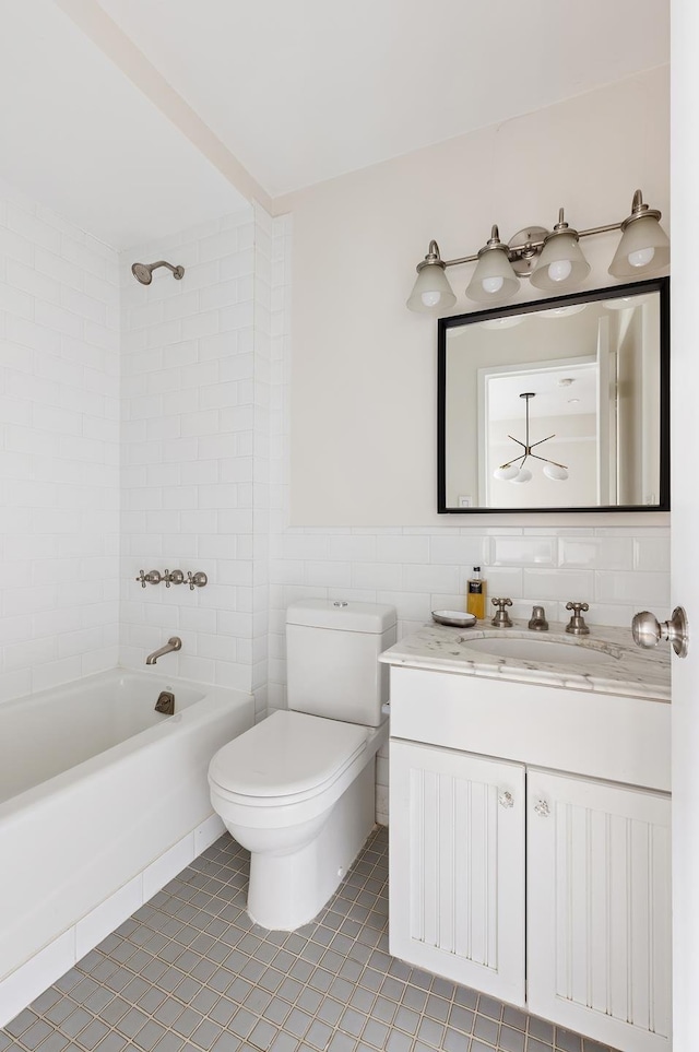 bathroom featuring toilet, tile walls, bathtub / shower combination, vanity, and tile patterned floors
