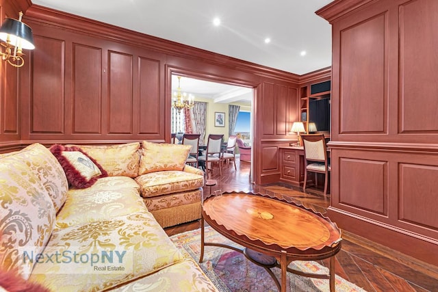 living room with a decorative wall, ornamental molding, recessed lighting, and a notable chandelier