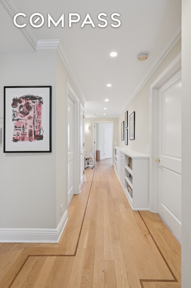 hallway with baseboards, light wood-type flooring, and ornamental molding