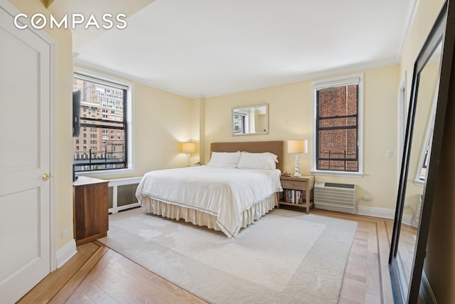 514 W End Ave Unit 8/9A, New York City, NY 10024 - bedroom with light wood-style flooring, radiator heating unit, an AC wall unit, ornamental molding, and baseboards