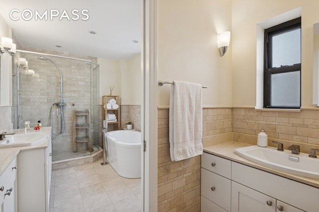 bathroom with a shower stall, a tub to relax in, tile walls, tile patterned floors, and vanity