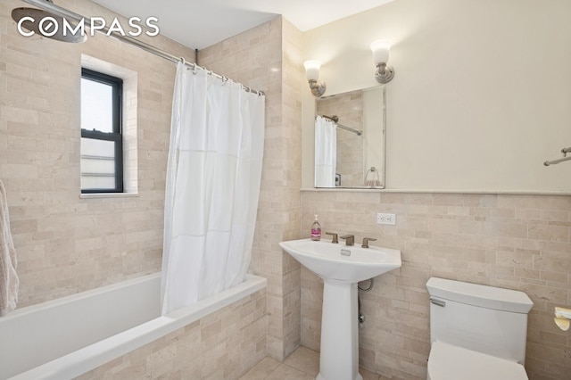 bathroom featuring toilet, tiled shower / bath combo, and tile walls