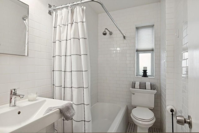 bathroom with tile walls, a sink, shower / bath combo with shower curtain, and toilet