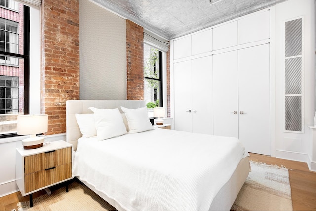 242 Lafayette St Unit 2N, New York City, NY 10012 - bedroom with light wood-type flooring, an ornate ceiling, a closet, and brick wall