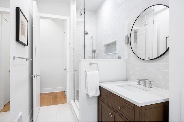 242 Lafayette St Unit 2N, New York City, NY 10012 - full bath featuring vanity, a stall shower, tasteful backsplash, and wood finished floors
