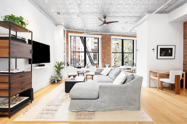 242 Lafayette St Unit 2N, New York City, NY 10012 - living room featuring wood finished floors, brick wall, an ornate ceiling, a ceiling fan, and baseboards