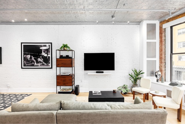 242 Lafayette St Unit 2N, New York City, NY 10012 - living area with wood finished floors, brick wall, baseboards, and track lighting