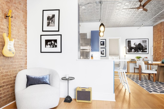 242 Lafayette St Unit 2N, New York City, NY 10012 - living area featuring brick wall, wood finished floors, a ceiling fan, an office area, and an ornate ceiling