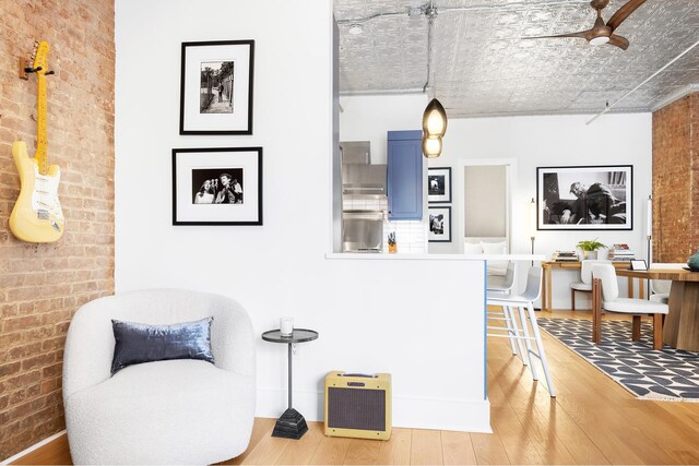 242 Lafayette St Unit 2N, New York City, NY 10012 - living area with brick wall, wood finished floors, a ceiling fan, and a desk