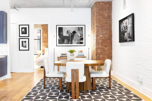242 Lafayette St Unit 2N, New York City, NY 10012 - dining space with light wood finished floors, brick wall, and baseboards