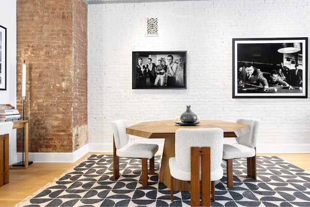 242 Lafayette St Unit 2N, New York City, NY 10012 - dining room featuring baseboards, wood finished floors, and brick wall