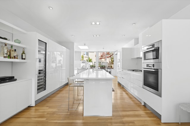 kitchen with light countertops, white cabinets, modern cabinets, light wood finished floors, and oven