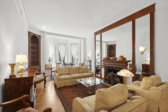 living room featuring a premium fireplace, wood finished floors, ornamental molding, and built in features