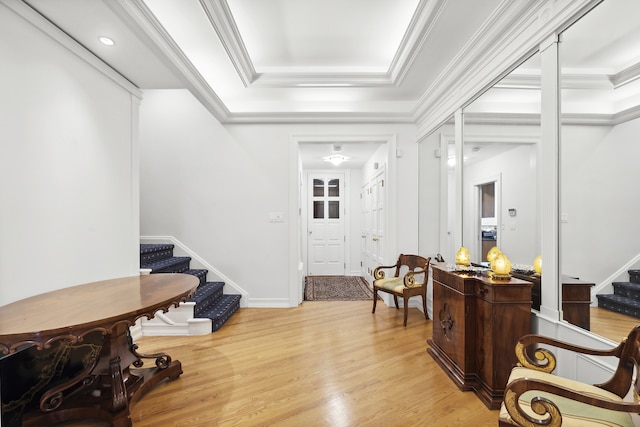 entryway featuring a tray ceiling, stairway, and light wood finished floors