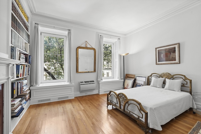 bedroom with ornamental molding, multiple windows, and wood finished floors