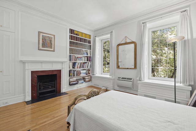 bedroom featuring a fireplace with flush hearth, multiple windows, ornamental molding, and a wall unit AC