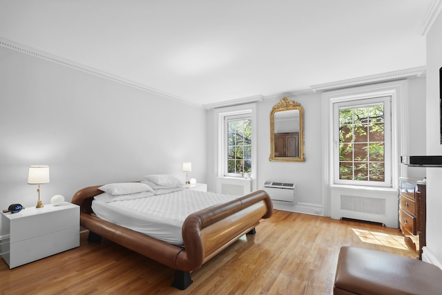 bedroom with radiator heating unit, light wood finished floors, multiple windows, and crown molding