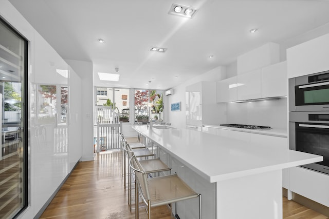 kitchen with modern cabinets, light countertops, gas stovetop, light wood-style floors, and white cabinetry