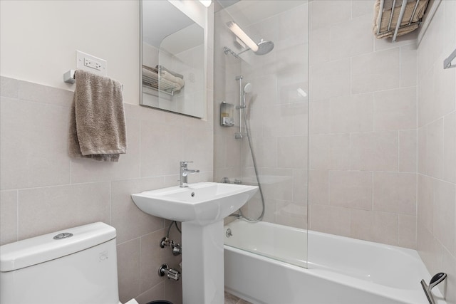 bathroom with tile walls, toilet, and  shower combination
