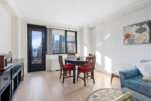 dining area featuring crown molding, baseboards, and light wood-style floors