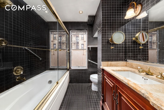 517 E 87th St Unit 1, New York City, NY 10128 - bathroom featuring tile walls, tile patterned flooring, toilet, enclosed tub / shower combo, and vanity