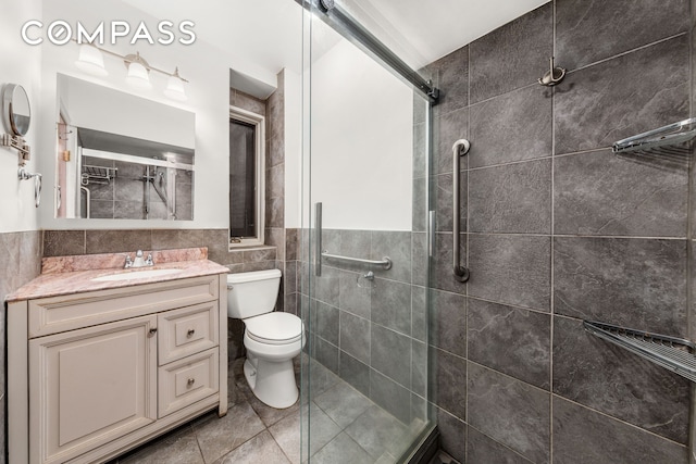 517 E 87th St Unit 1, New York City, NY 10128 - full bathroom featuring tile walls, a tile shower, vanity, toilet, and tile patterned floors