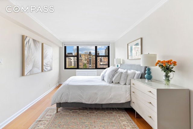bedroom featuring wood finished floors, ornamental molding, and baseboards