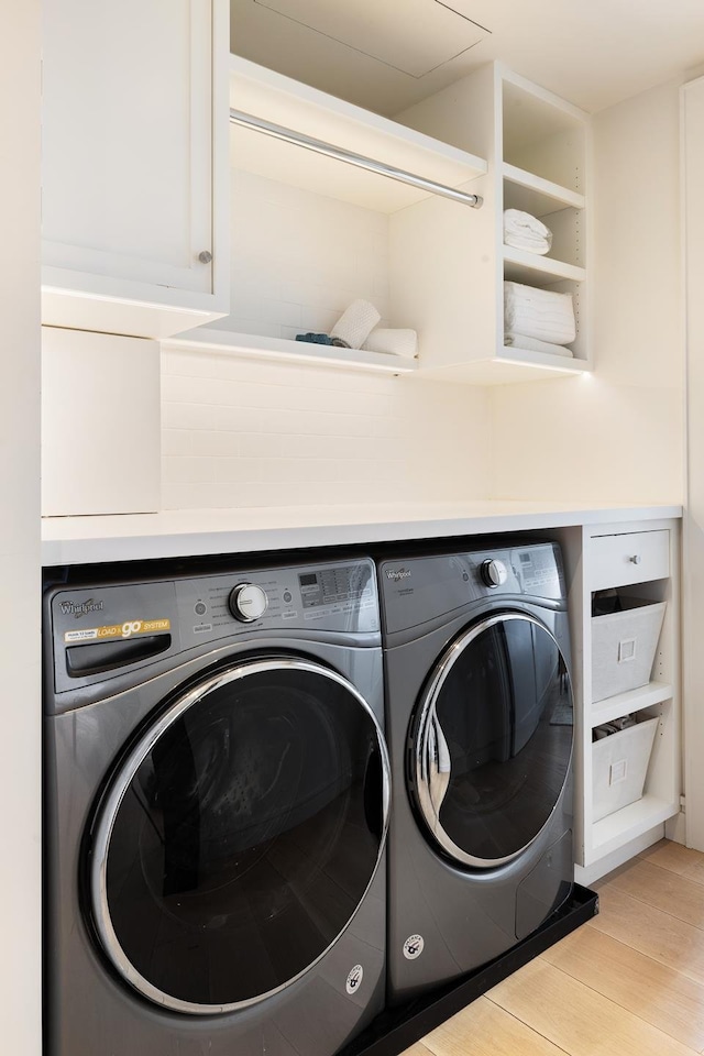 clothes washing area with wood finished floors and washer and dryer