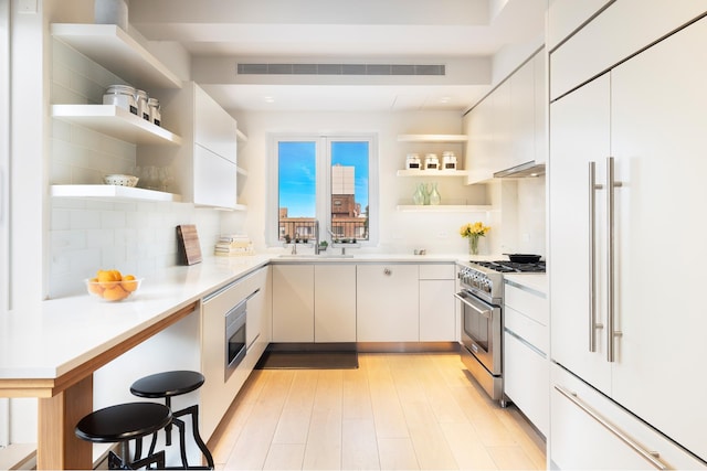 kitchen with open shelves, visible vents, built in appliances, and a sink