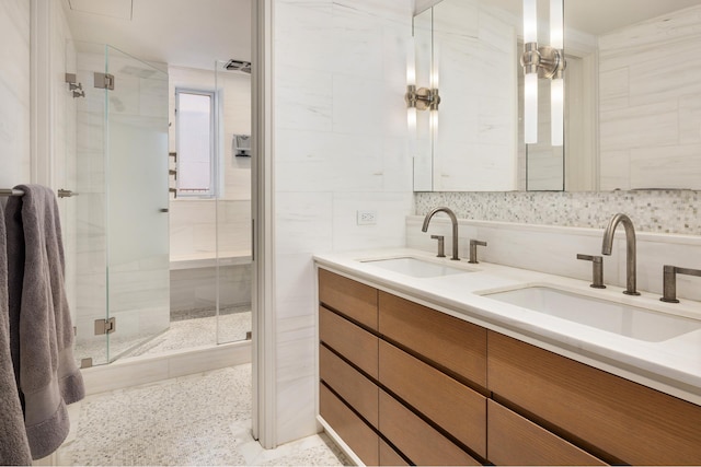 full bathroom with speckled floor, double vanity, a shower stall, and a sink