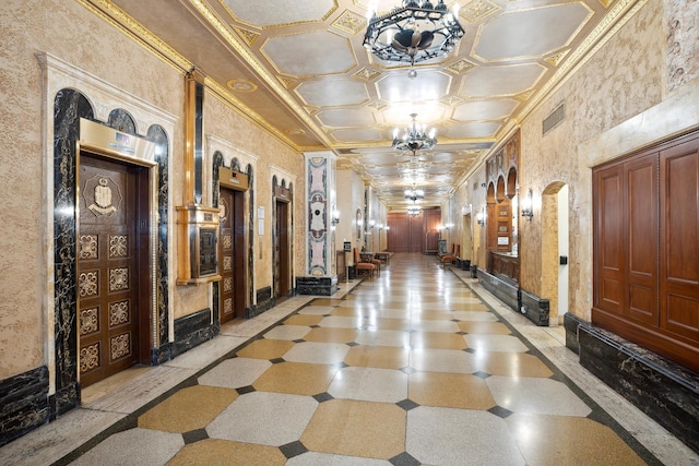hallway with an inviting chandelier, ornamental molding, and visible vents